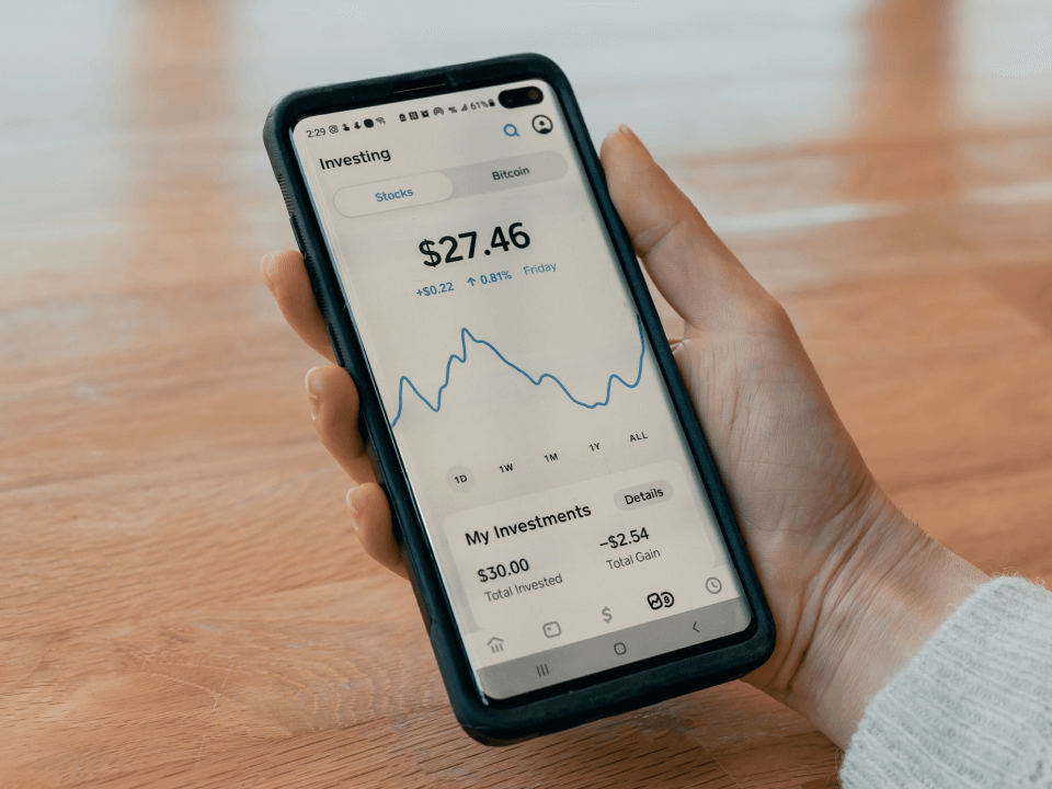 Pertson holding phone with stock chart displayed