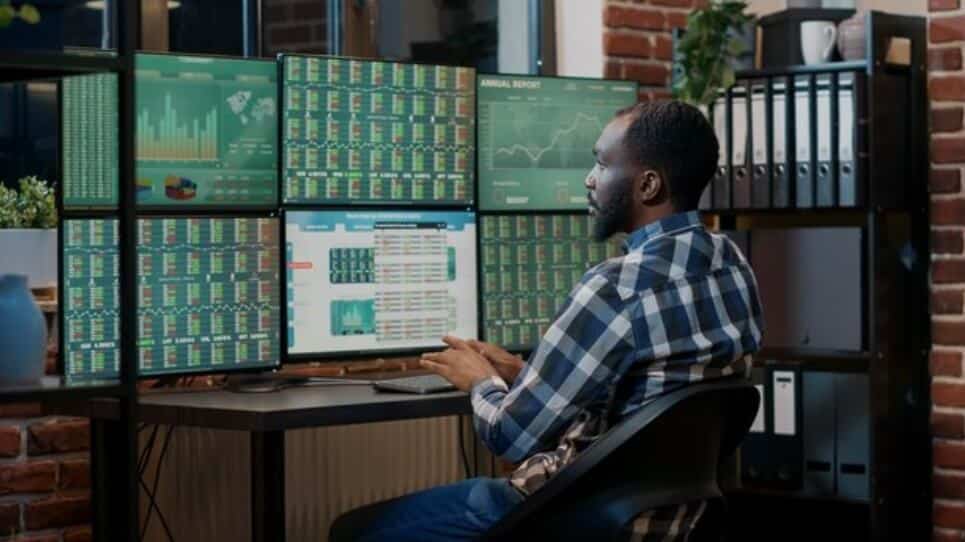 man sitting infront of computer showing trading charts