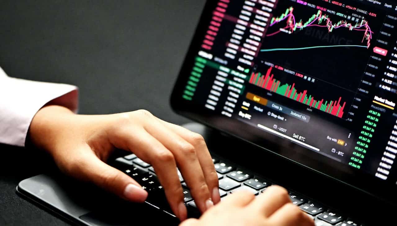 hands typing on laptop showing forex chart