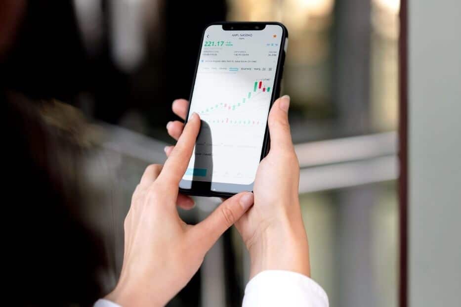 woman holding phone showing a trading chart