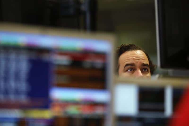 A man observes a computer screen filled with stock market information and graphs.
