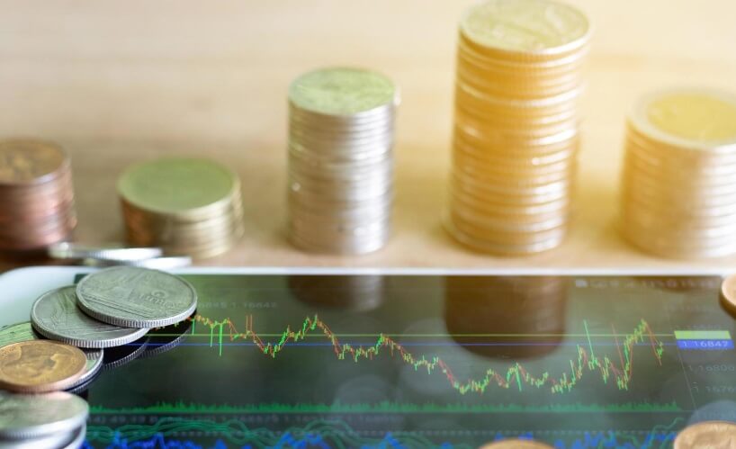 stack of coins with tablet showing forex chart