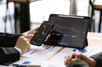 man holding phone with tablet both showing trading chart