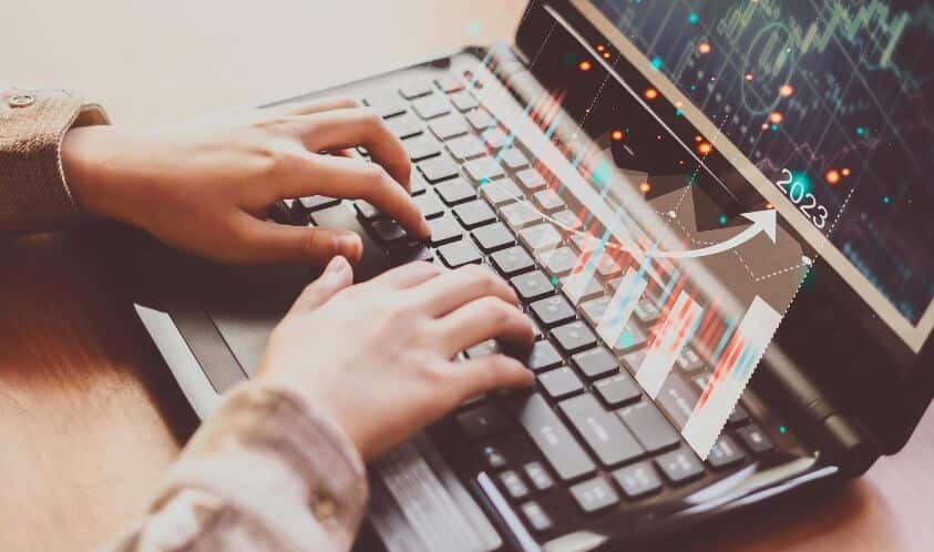 fingers typing on laptop showing virtual forex chart
