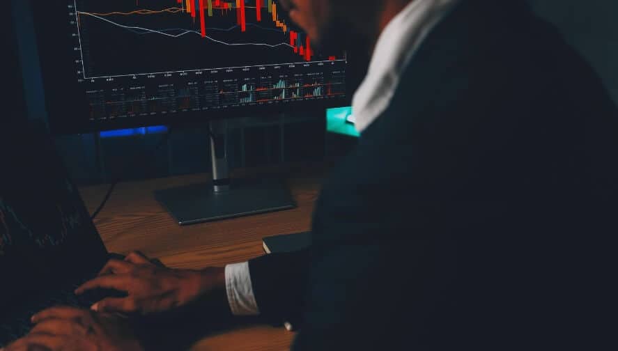 side profile of man trading forex of PC that is red