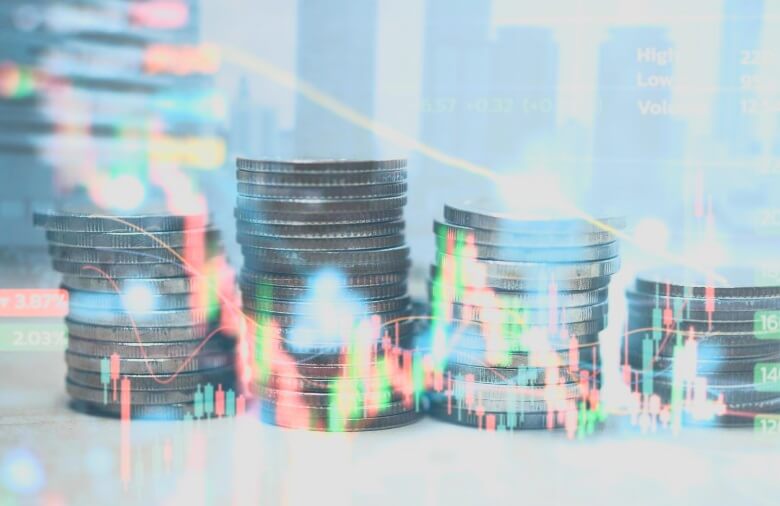 stacked coins behind virtual forex chart that is green and red