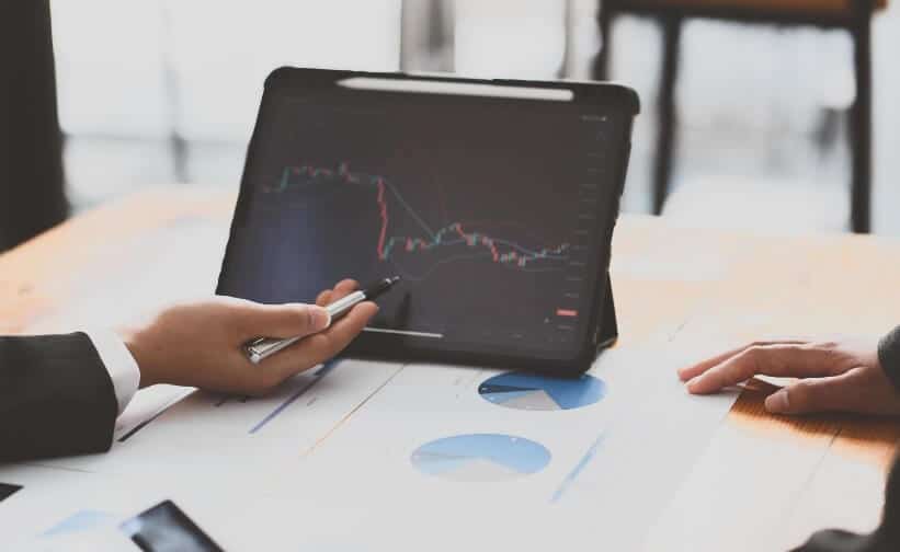 person pointing to tablet showing forex chart that is red and green