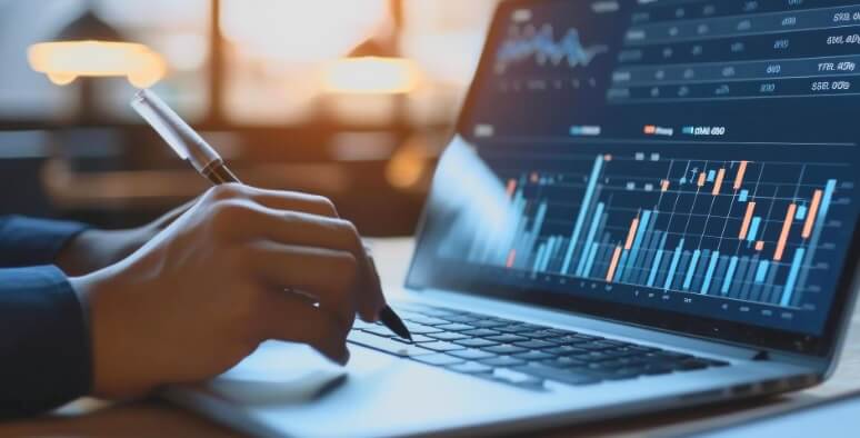 laptop showing forex chart and hand with pen