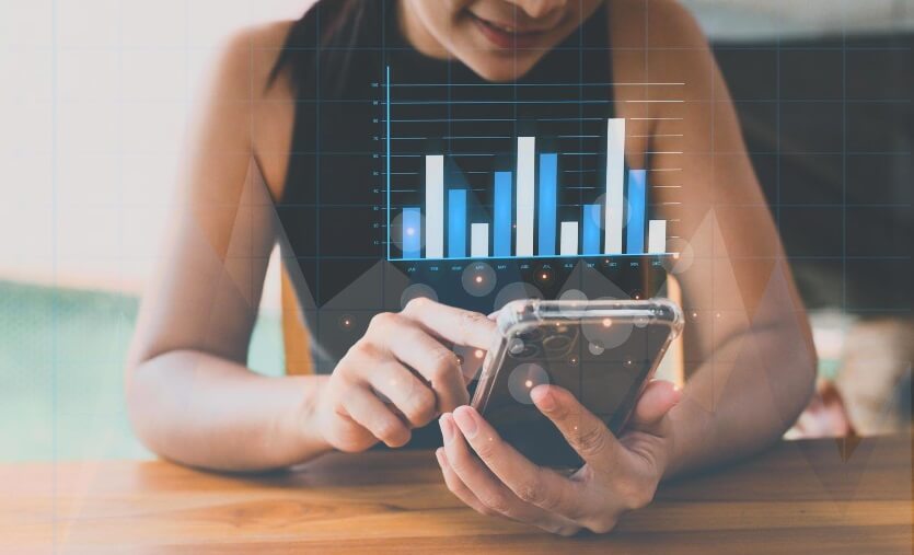 woman holding phone with virtual trading chart